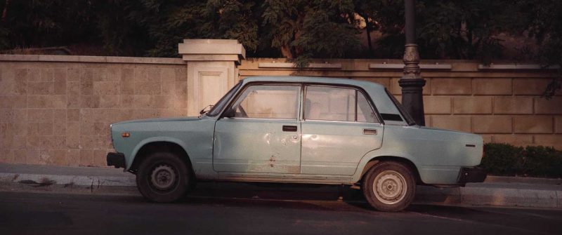 Standbild aus Lufthansa – City of the Month: Baku. Ein alter hellblauer Lada vor einer Mauer.