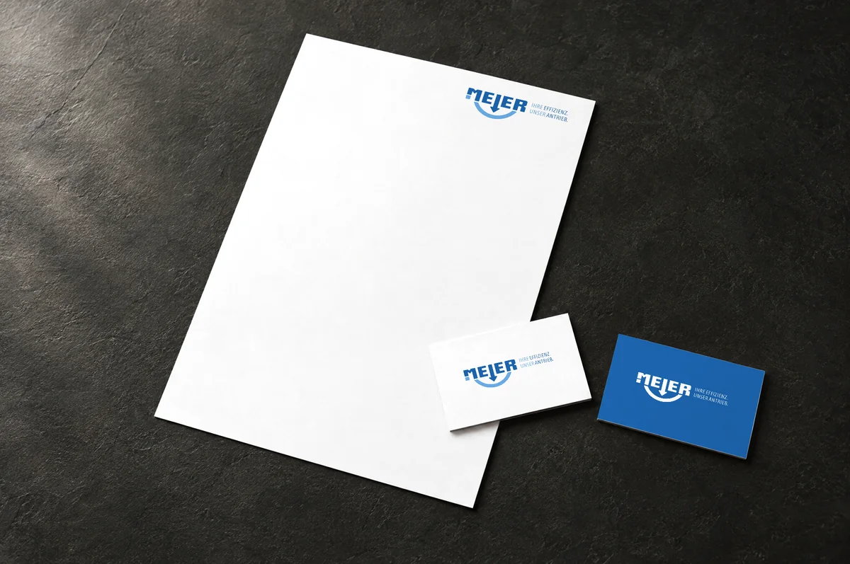 Mockup: Briefbogen und zwei Visitenkarten mit dem neuen Heinrich-Meier-Logo, eine Karte in Blau mit weißem Logo und Claim.
